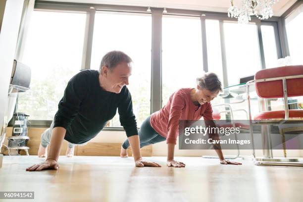 happy senior couple doing push-ups at home - liegestütze stock-fotos und bilder