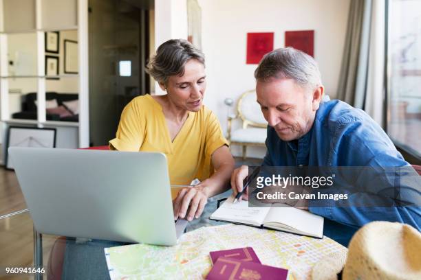 mature woman planning vacation with man at home - vacation planning stock pictures, royalty-free photos & images