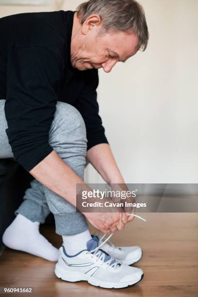 senior man wearing sports shoes at home - tieing shoelace stock pictures, royalty-free photos & images