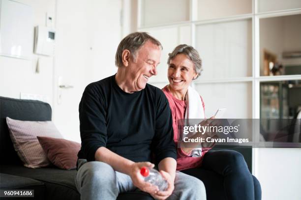 happy senior couple using smart phone in living room - baby boomer stock pictures, royalty-free photos & images