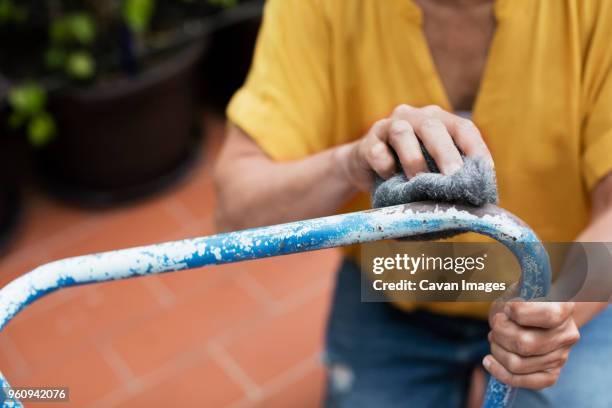 midsection of woman scrubbing chair with steel wool at yard - brillos stockfoto's en -beelden