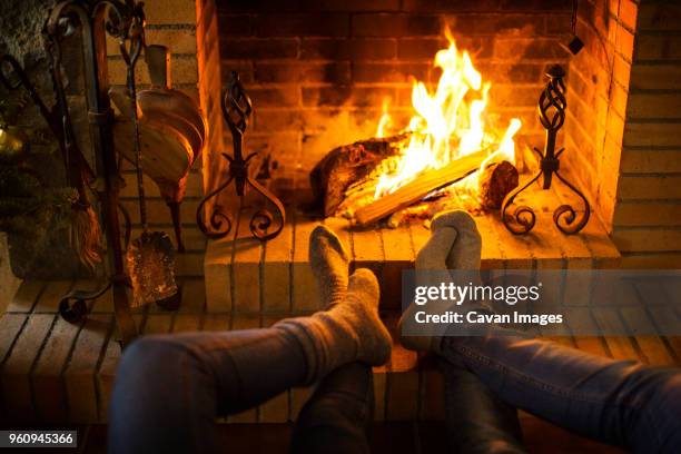 low section of couple resting by fireplace at home - socks fireplace stock pictures, royalty-free photos & images