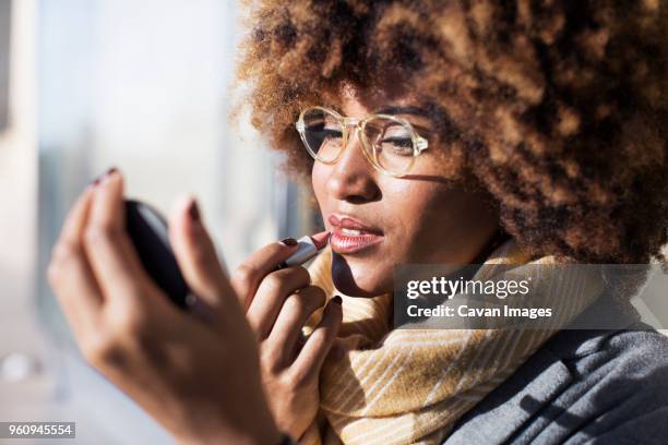close-up of woman applying lipstick at bus stop - woman lipstick stock pictures, royalty-free photos & images