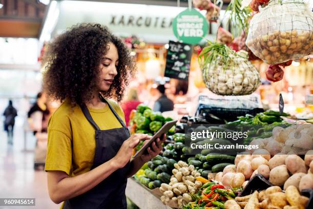 vendor using tablet computer at market stall - market trader fotografías e imágenes de stock