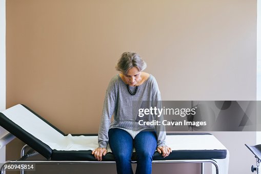 Senior patient sitting on bed against wall at hospital Senior patient sitting on bed against wall at hospital