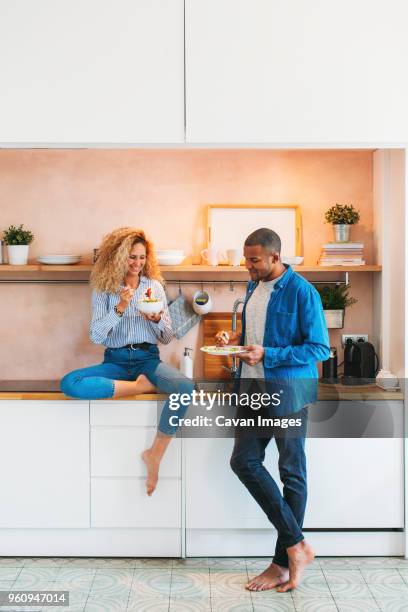 full length of multi-ethnic couple eating salad and sandwich in kitchen - black man full length stock pictures, royalty-free photos & images