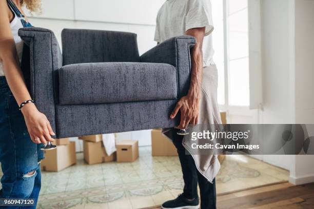 couple carrying armchair while standing at new house - new husband stock pictures, royalty-free photos & images
