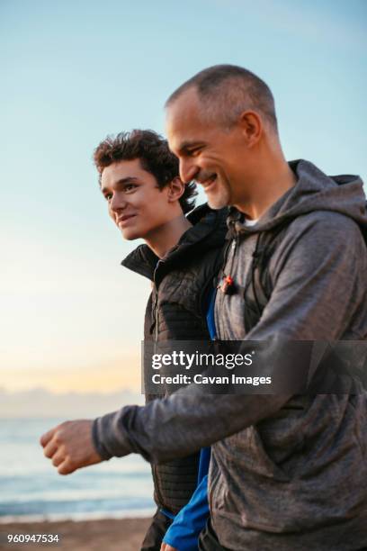 side view of happy father and son walking at beach against sky - walking side view stock pictures, royalty-free photos & images