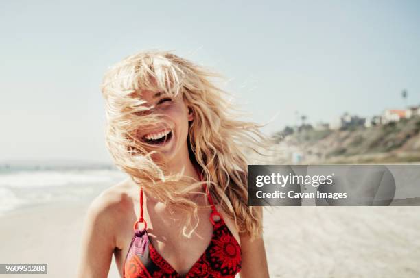 portrait of cheerful woman on beach - cheveux au vent photos et images de collection