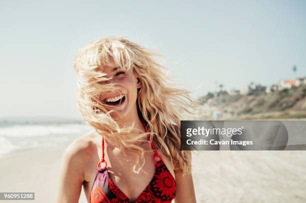 portrait of cheerful woman on beach - capelli biondi foto e immagini stock