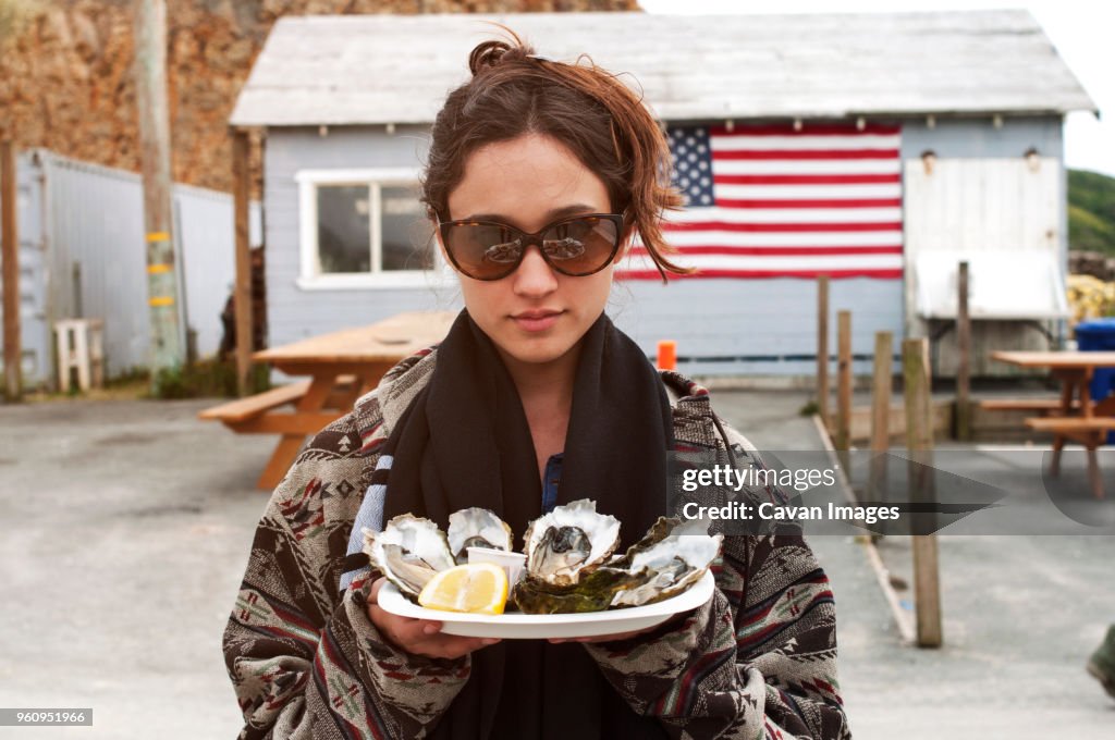 Woman holding oysters in plate outside house