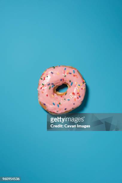 overhead view of doughnut on blue background - beignet photos et images de collection