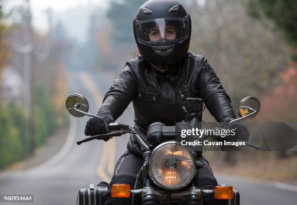 female biker wearing crash helmet while riding motorcycle on road - biker foto e immagini stock