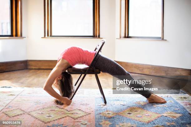 woman stretching on chair at home - yoga chair stockfoto's en -beelden