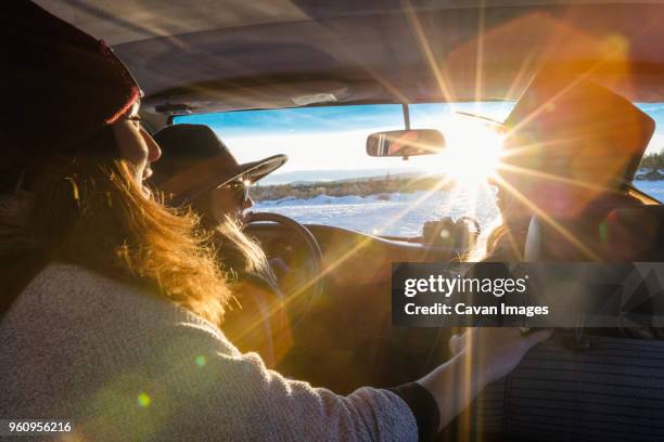 female friends sitting in car on sunny day during winter - winter car stock pictures, royalty-free photos & images