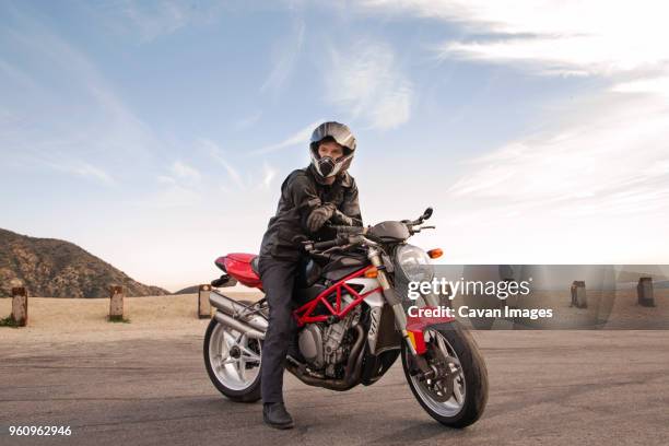 portrait of biker sitting on motorcycle wearing helmet - motorcycle biker photos et images de collection