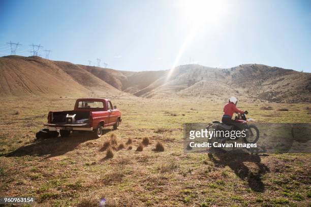 rear view of female biker riding motorcycle on arid landscape during summer - arid stock pictures, royalty-free photos & images