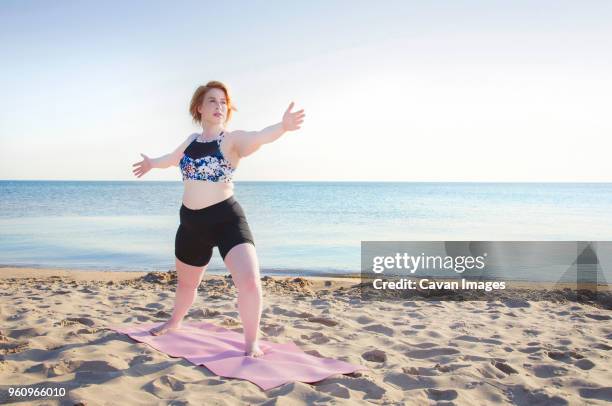 woman practicing yoga pose at beach against clear sky - short hair for fat women stock pictures, royalty-free photos & images