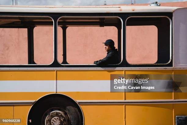 man looking away while sitting in bus seen through window - bus window stock pictures, royalty-free photos & images