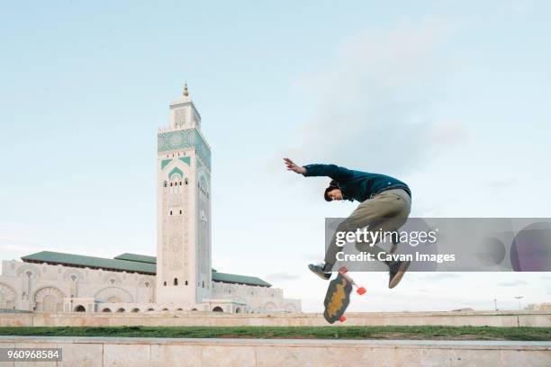 side view of man skateboarding against mosque hassan ii - casablanca photos et images de collection
