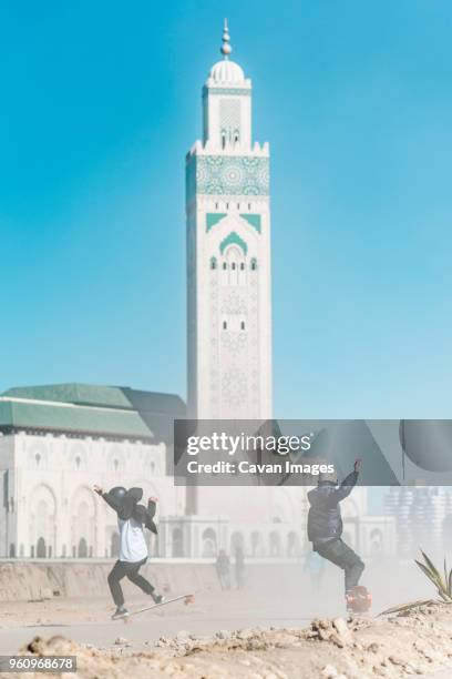 full length of friends skateboarding against mosque hassan ii - floating mosque bildbanksfoton och bilder