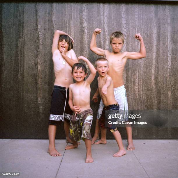 portrait of boys flexing muscles while standing against wall - group of people flexing biceps stock pictures, royalty-free photos & images