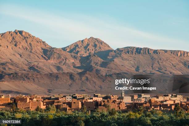 high angle view of houses in village by atlas mountains against sky - atlas mountains morocco stock pictures, royalty-free photos & images