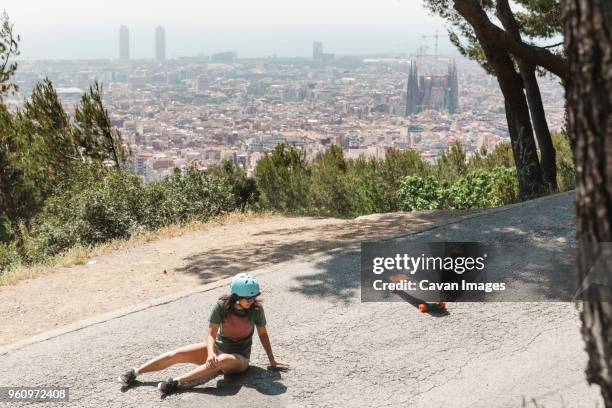 high angle view of woman falling from skateboard on road - skateboard fall stock-fotos und bilder