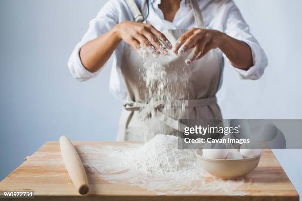 midsection of woman kneading dough on table while standing against wall in kitchen - rolling pin stock pictures, royalty-free photos & images