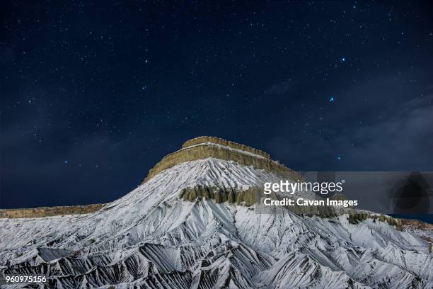 scenic view of snowcapped mountain against starry sky at night - be boundless summit stock pictures, royalty-free photos & images
