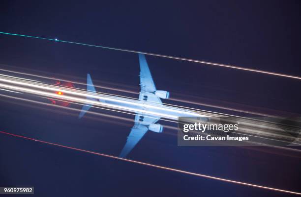 low angle view of signal mast against light trails and airplane in sky at night - low flying aircraft stockfoto's en -beelden