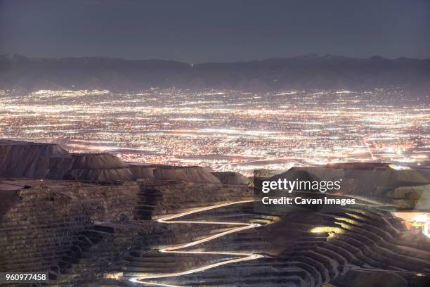 high angle view of bingham canyon against illuminated cityscape - bingham canyon mine stock pictures, royalty-free photos & images
