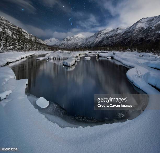scenic view of lake against snowcapped mountains at chugach state park during night - chugach state park stock-fotos und bilder
