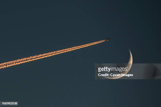 low angle view of airplane flying against clear sky at night - rastro de avião - fotografias e filmes do acervo