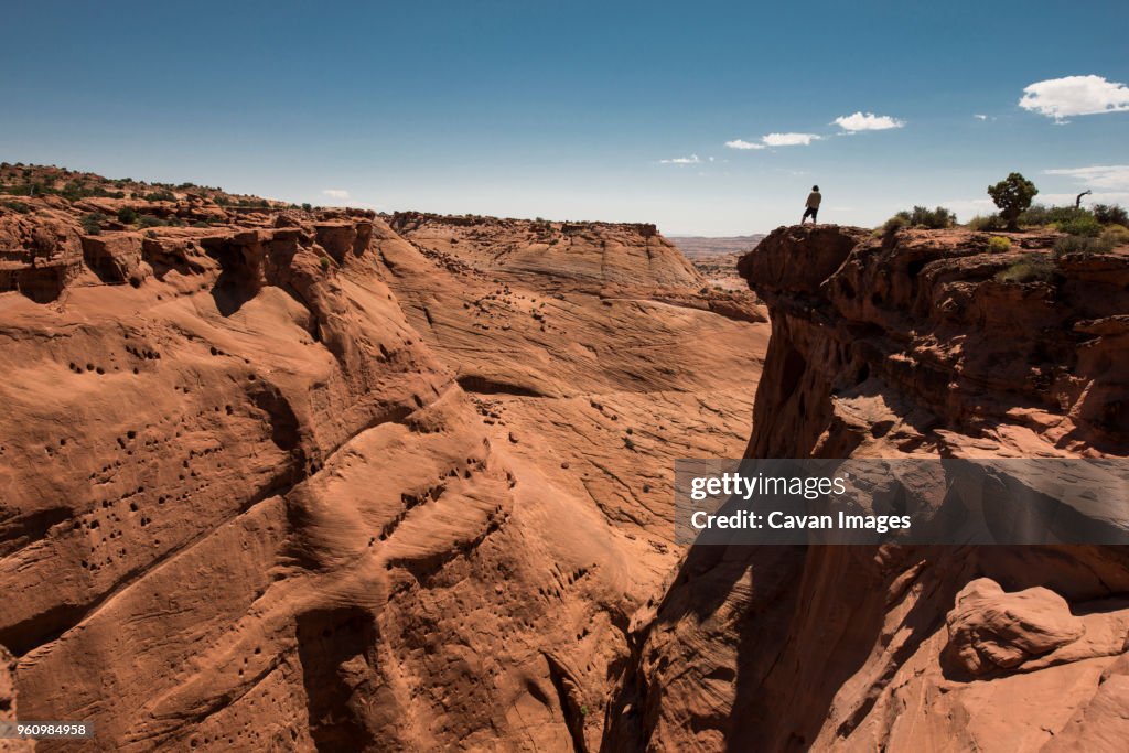 Mid distance view of man standing on cliff at Grand Staircase-Escalante National Monument against sky