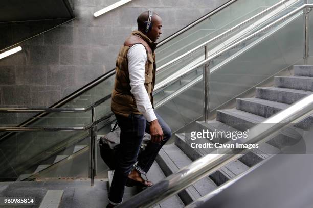 side view of man climbing steps at subway station - escalator side view stock pictures, royalty-free photos & images