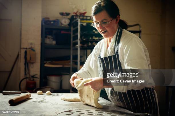 female baker preparing bread dough in commercial kitchen - bäckerin stock-fotos und bilder