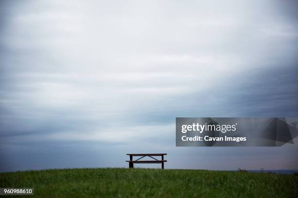 bench with table on grass under overcast sky - empty picnic table stock pictures, royalty-free photos & images