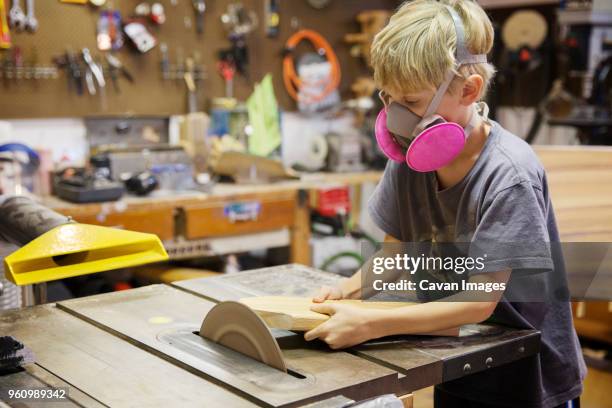 boy cutting wood with table saw in workshop - table saw stock pictures, royalty-free photos & images