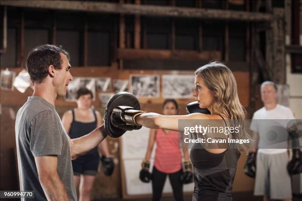 confident boxers practicing in health club - old man young woman stockfoto's en -beelden
