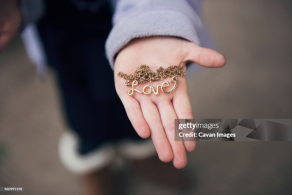 Overhead view of hand holding locket with love text on street