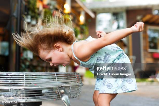 girl screaming while enjoying breeze from electric fan - electric fan stock pictures, royalty-free photos & images