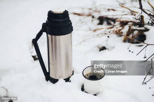 close-up of insulated drink container by mug with black coffee on snow - insulated drink container foto e immagini stock