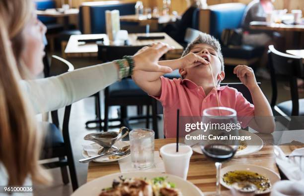 mother stopping son eating noodles in restaurant - childish stock-fotos und bilder