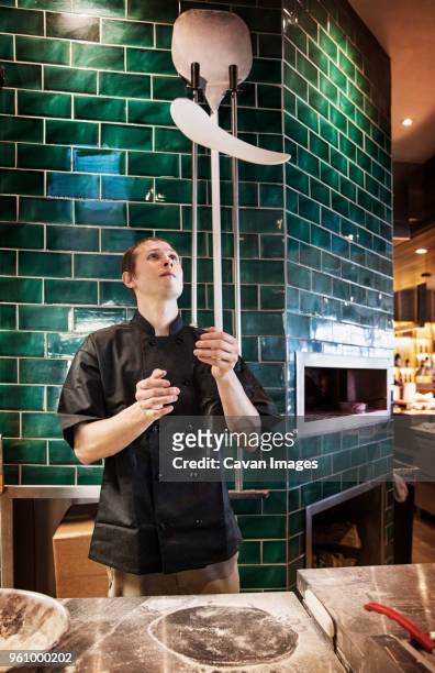 male chef tossing pizza dough in commercial kitchen - pizza toss foto e immagini stock