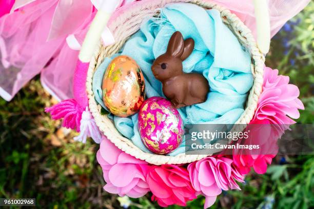 overhead view of girl with easter eggs and bunny in basket - easter basket stock pictures, royalty-free photos & images