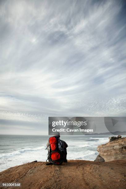 man sitting on edge of cliff - sitting on edge of cliff stock pictures, royalty-free photos & images