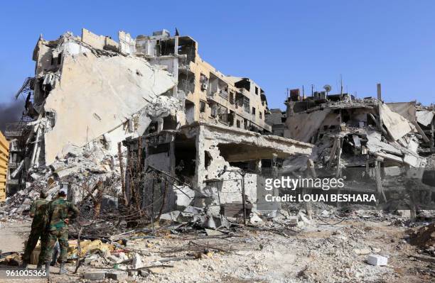 Syrian government forces stand in front of a destroyed building at the entrance of the Hajar al-Aswad district on the southern outskirts of Damascus...