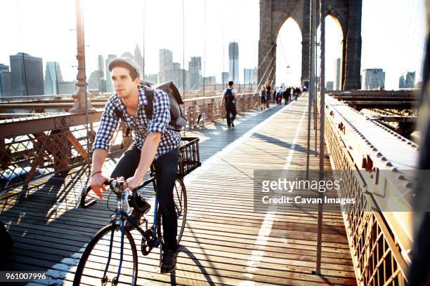 man riding bicycle on brooklyn bridge against clear sky - ブルックリン橋 ストックフォトと画像