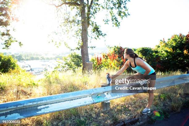 woman looking away while stretching hamstrings on road - hamstring stock pictures, royalty-free photos & images